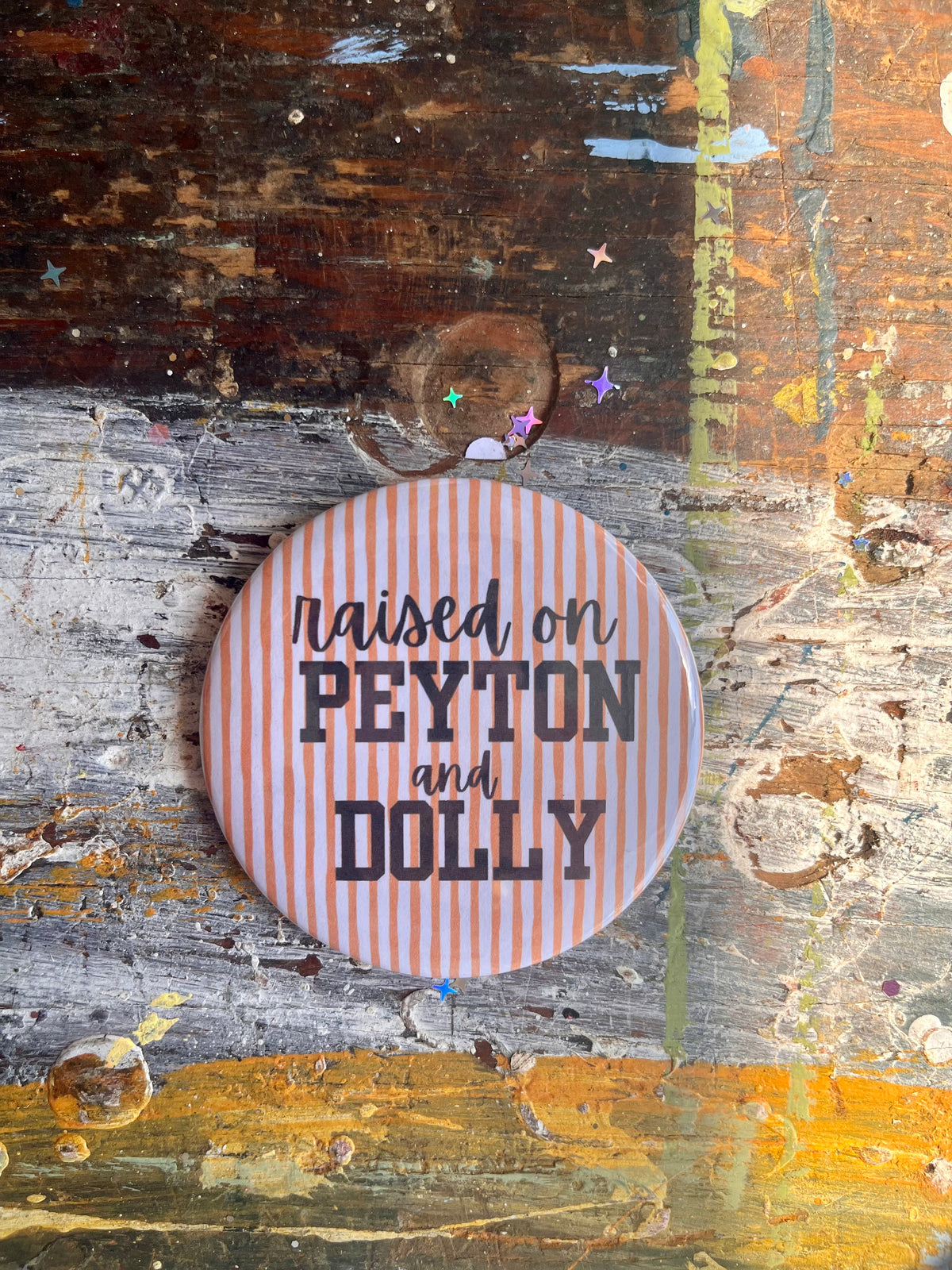 "raised on PEYTON and DOLLY" black on orange/white stripes button